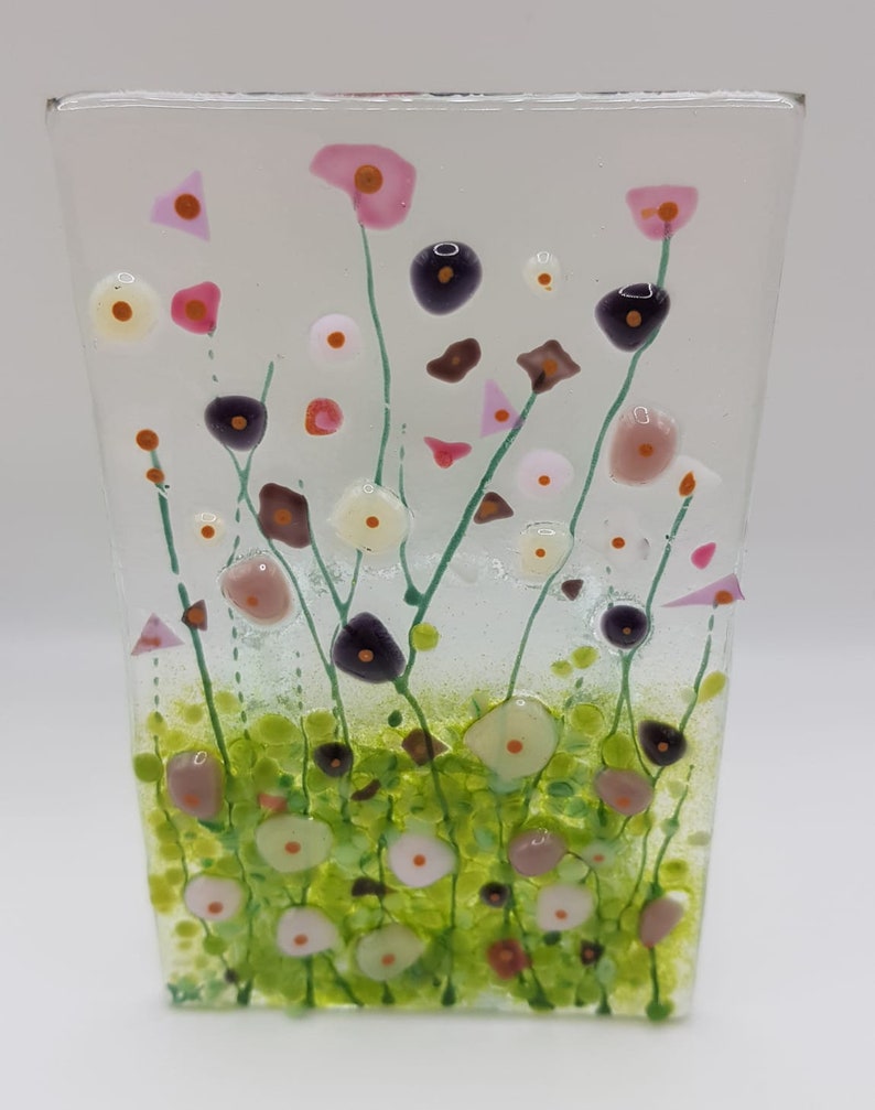 May include: A glass panel with a colorful floral design. The flowers are pink, white, and green. The background is clear glass.