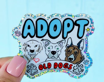 May include: A sparkly sticker with a blue and white design that says "Adopt Old Dogs". The sticker features three dogs with hearts and paw prints.