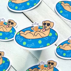 May include: Six yellow Labrador Retriever dogs wearing sunglasses are relaxing in blue and green inflatable pool floats with bone and ball designs. Each dog is holding a glass of beer.