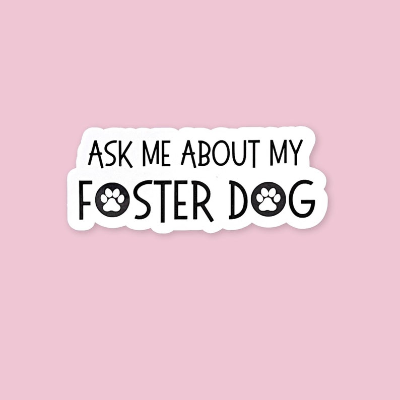 May include: White sticker with black text that reads "Ask me about my foster dog" with a paw print icon on either side of the word "foster".