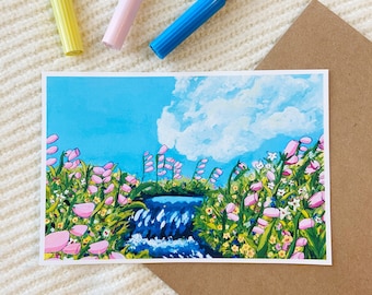 Könnte beinhalten: Ein Kunstdruck mit einer Wasserfallszene mit rosa Blumen, grünem Laub und einem blauen Himmel mit Wolken. Drei farbige Marker in Gelb, Rosa und Blau sind über dem Druck positioniert. Ein brauner Umschlag ist ebenfalls sichtbar.