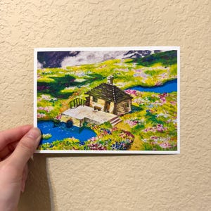 May include: A watercolor painting of a small, brown cabin with a stone porch and a wooden bridge. The cabin is surrounded by a field of colorful wildflowers and two small blue ponds.