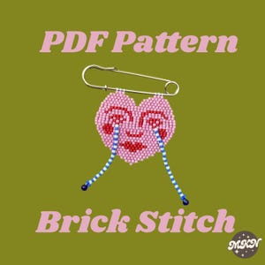 May include: A pink beaded heart-shaped pin with a face design, attached to a silver safety pin. The heart has red lips and eyes with blue and white beaded tears. Text on the image reads "PDF Pattern" and "Brick Stitch".