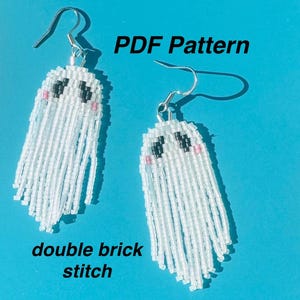 Puede incluir: Un par de pendientes de fantasma de cuentas blancas con ojos negros y mejillas rosadas. Los pendientes están hechos con un punto de ladrillo doble y tienen ganchos plateados. El texto "PDF Pattern" está escrito encima de los pendientes y "double brick stitch" está escrito debajo de los pendientes.