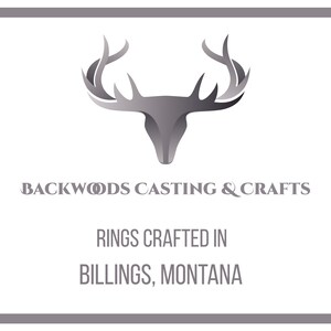May include: A silver deer head logo with antlers against a white background. The text "Backwoods Casting & Crafts" is below the logo. The text "Rings Crafted in Billings, Montana" is below the text.
