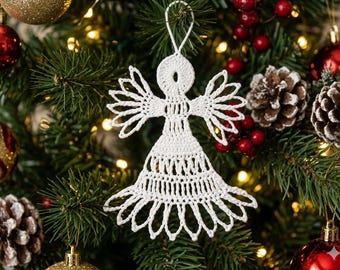 Könnte beinhalten: Ein weißes gehäkeltes Engel-Ornament mit einem komplizierten spitzenartigen Muster, einem runden Kopf, ausgebreiteten Flügeln und einem ausgestellten Rock. Das Ornament hat oben eine kleine weiße Schlaufe zum Aufhängen am Weihnachtsbaum.