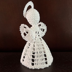 Può includere: Ornamento di angelo bianco lavorato a uncinetto con un'aureola e ali.