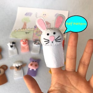 May include: A set of felt finger puppets featuring a lion, dog, pig, cat, monkey, sheep, hippopotamus, and a rabbit. The puppets are white with embroidered facial features. The rabbit puppet is on a finger with a speech bubble that says "Pdf Pattern".