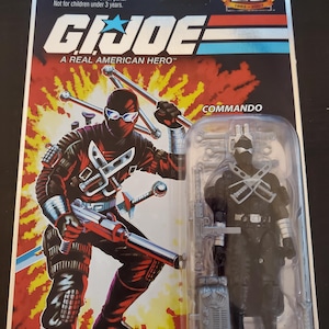 May include: A G.I. Joe Commando action figure in its original packaging. The packaging features a red and black graphic of the Commando character with weapons. The figure is in a clear plastic case. The packaging reads "A Real American Hero."