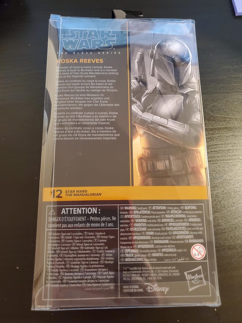 May include: A Star Wars: The Mandalorian action figure of Koska Reeves, a Mandalorian warrior, in a black and gray suit with a blue helmet. The figure is holding a blaster rifle. The packaging is black and yellow with the Star Wars logo and the character's name.