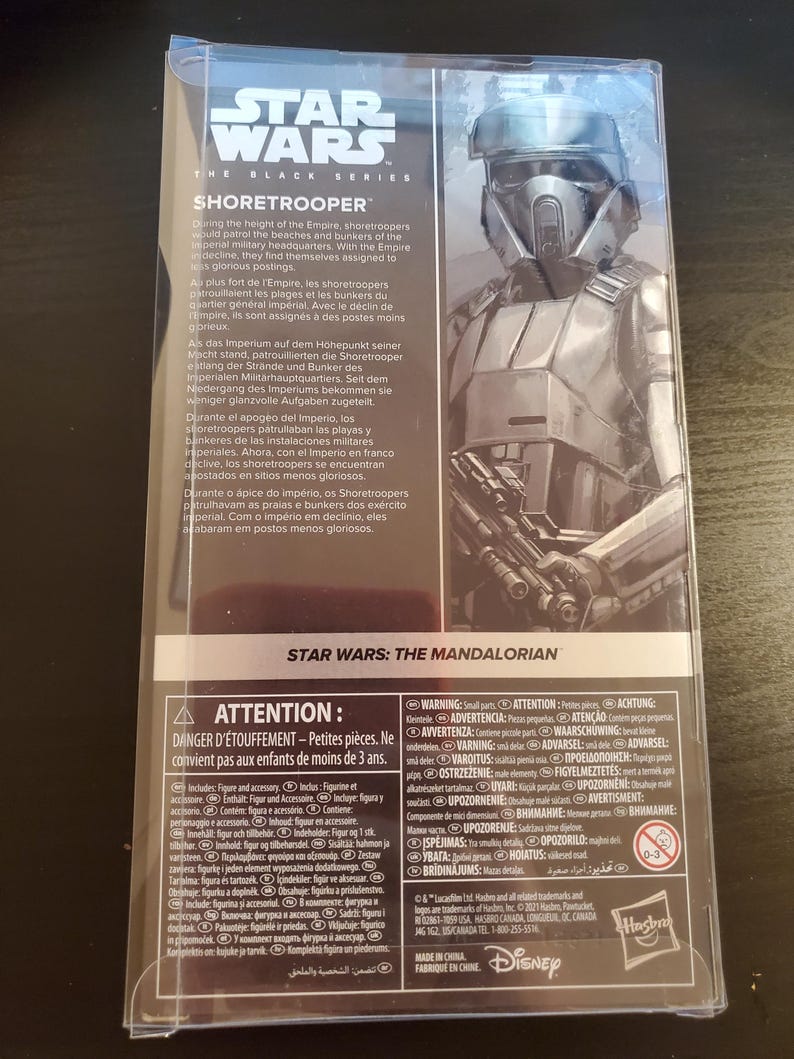 May include: A Star Wars: The Black Series Shoretrooper action figure. The figure is posed with a blaster rifle and is wearing a white and gray helmet and armor. The packaging includes a warning about choking hazards for children under 3 years old.