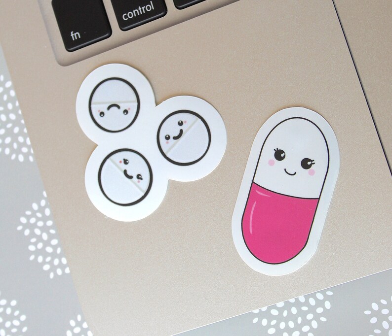 May include: A collection of stickers featuring cartoon pill designs. One sticker shows a pink and white capsule with a smiling face. Another sticker has three white pills with different facial expressions.