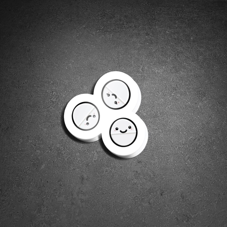 May include: A cluster of three white, circular objects with cartoon faces. Each object has a different expression: one is smiling, one is neutral, and one is frowning. The objects are arranged in a cloverleaf pattern against a dark gray background.