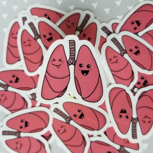 May include: A set of pink and white stickers featuring cartoon lungs with smiling faces. The lungs are drawn in a simple, whimsical style and have black outlines. The stickers are perfect for adding a touch of humour to any surface.