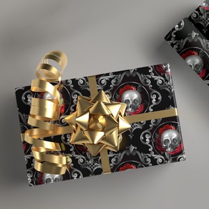 May include: A black and silver gift wrap with a skull and red roses design. The gift is wrapped with a gold ribbon and bow.
