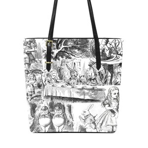 Puede incluir: Una bolsa de mano de lona negra y blanca con un estampado de ilustraciones de Alicia en el Pa&iacute;s de las Maravillas. El estampado incluye a Alicia, el Sombrerero Loco, la Liebre de Marzo, el Gato de Cheshire y otros personajes del libro.