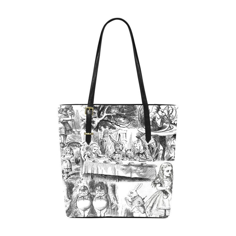 Puede incluir: Una bolsa de mano de lona negra y blanca con un estampado de ilustraciones de Alicia en el Pa&iacute;s de las Maravillas. El estampado incluye a Alicia, el Sombrerero Loco, la Liebre de Marzo, el Gato de Cheshire y otros personajes del libro.