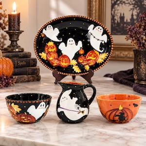 May include: A ceramic Halloween set featuring an oval platter, a pitcher, and two bowls. The black platter displays white ghosts and orange pumpkins. The black pitcher shows a ghost with a broom, while the orange bowl features a black witch silhouette.