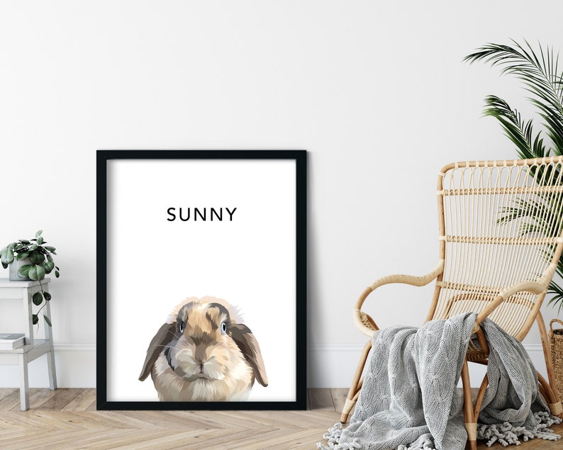 Op de afbeelding: Een zwart ingelijst print met een witte achtergrond en een cartoon afbeelding van een bruin en wit konijn met de naam "SUNNY" in zwart bovenaan.