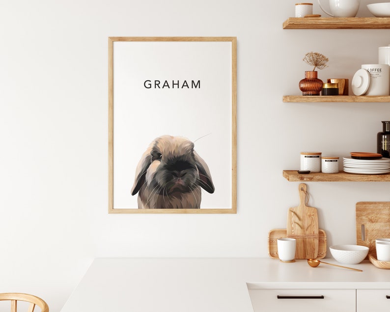 Op de afbeelding: Een ingelijst afdruk met een bruin konijn met hangoren en de naam "GRAHAM" gedrukt in zwarte tekst.