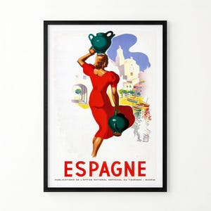 May include: A framed vintage travel poster featuring a figure in a red dress carrying two dark green jugs. The background shows a coastal town with boats and buildings. The text ESPAGNE and PUBLICATIONS DE L'OFFICE NATIONAL ESPAGNOL DU TOURISME MADRID appear.