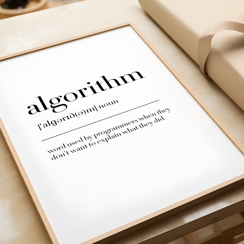 May include: A framed print with a black and white definition of the word "algorithm". The definition reads: "['algərı&eth;(ə)m] noun word used by programmers when they don't want to explain what they did."