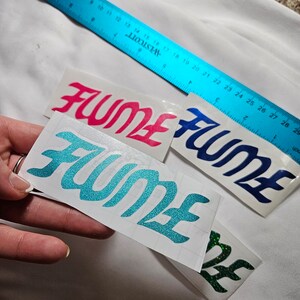 May include: Three vinyl stickers with the word "FUME" in different colors. The stickers are on a white background. The colors are pink, blue, and teal.