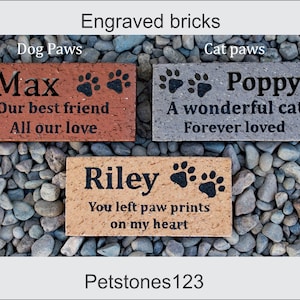 May include: Three engraved bricks with paw prints and personalized messages. The bricks are red, gray, and brown. The messages read "Max Our best friend All our love", "Poppy A wonderful cat Forever loved", and "Riley You left paw prints on my heart".