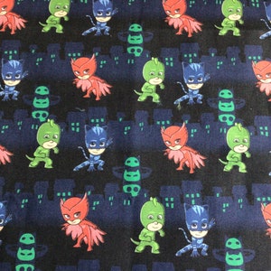 May include: Dark blue fabric featuring a repeating pattern of cartoon characters in red, green, and blue costumes. The characters are set against a backdrop of stylized city silhouettes in a darker shade of blue.