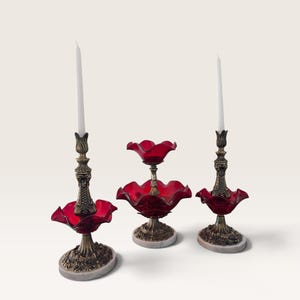 Peut inclure: Deux bougeoirs en laiton avec des bobèches en verre rouge à bords ondulés et des bougies blanches, accompagnés d'un plat de service central à deux niveaux en verre rouge ondulé avec pied en laiton et base en marbre circulaire.