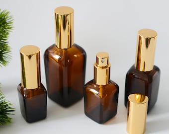May include: Set of five amber glass bottles with gold spray tops and caps. The bottles are various sizes and shapes.