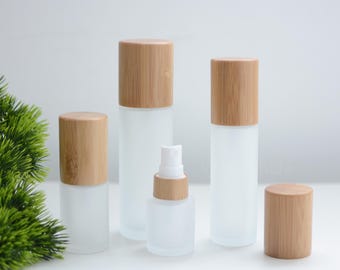 May include: A collection of frosted glass bottles and jars with natural bamboo lids. The set includes various sizes, from small spray bottles to larger cylindrical containers, all with a minimalist aesthetic.