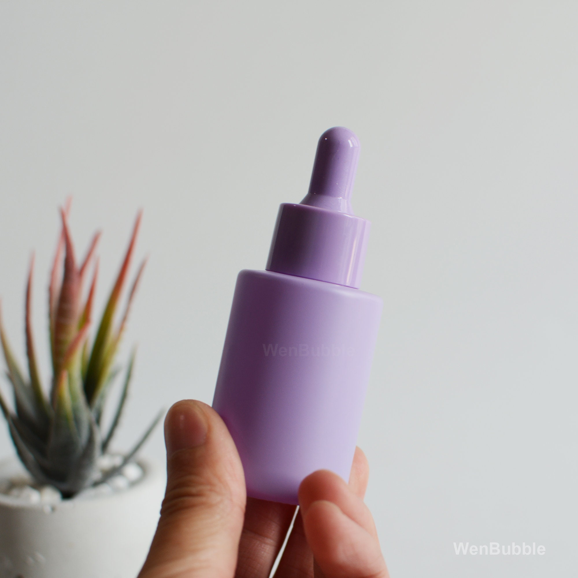Flacon de pipette violet en verre plastique cosmétique. Fleurs de