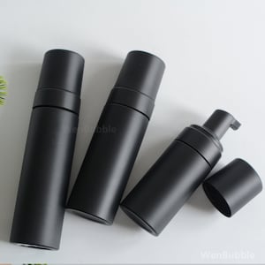 May include: Three black plastic bottles with pump tops. The bottles are empty and ready to be filled with liquid soap, lotion, or other products.