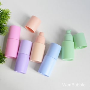 May include: A collection of pastel pump bottles in pink, lilac, peach, blue, and green. Each bottle has a matching cap, with one cap removed. The bottles are arranged on a white surface. The text "WenBubble" is visible.
