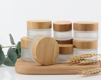 May include: Set of six frosted glass jars with bamboo lids. The jars are arranged in a pyramid shape on a wooden surface.