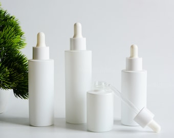 May include: Four white frosted glass bottles with dropper tops. The bottles are all the same size and shape, and they are arranged in a row on a white surface. The bottles are empty and ready to be filled with liquid.
