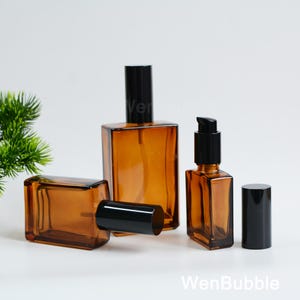 May include: Amber glass perfume bottles with black caps. One bottle has a pump dispenser. The bottles are rectangular and have a modern design. The image includes the text "WenBubble".