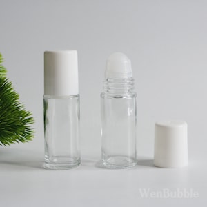 May include: Two clear glass roller bottles with white caps. The bottles are empty and ready to be filled with essential oils or other liquids.