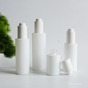 May include: Three white frosted glass bottles with dropper tops and a separate dropper. The bottles are all the same size and shape, and they are arranged in a row on a white surface.