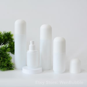 Peut inclure: Quatre flacons en plastique blanc avec des bouchons ronds. Les flacons sont de tailles diff&eacute;rentes et sont dispos&eacute;s en rang&eacute;e sur une surface blanche. Les flacons sont vides et ne portent aucune &eacute;tiquette.