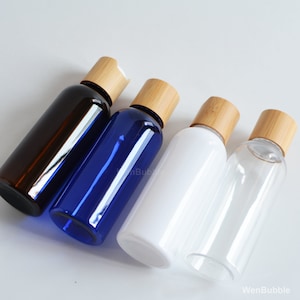 May include: Four plastic bottles with bamboo lids. The bottles are clear, blue, brown, and white. The bottles are all the same size and shape.