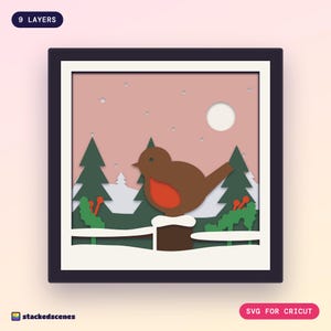 Finished 9-layer robin paper shadow box in a dark frame: a round robin on a snowy fence post with holly, spruces and a pale sun in a rosy sky.