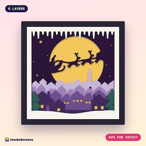 Finished 8-layer paper shadow box: a sleigh and reindeer silhouette crossing a big gold moon above purple snowy rooftops with glowing windows.