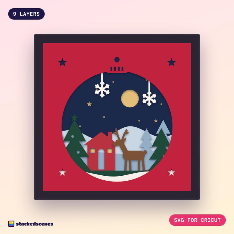 Finished 9-layer Christmas bauble paper shadow box: a snowy woodland with a red cabin, reindeer and pines seen through a red bauble-shaped window.