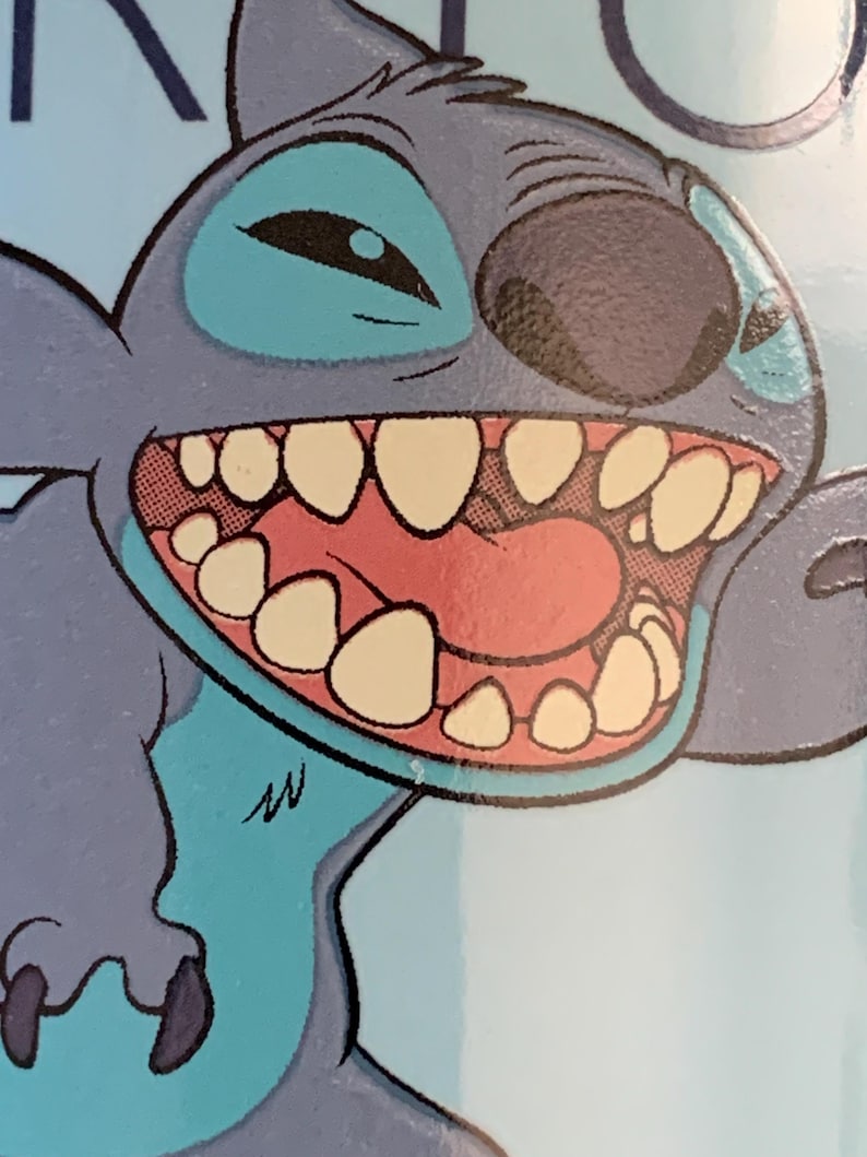 May include: A blue and gray cartoon character with a wide open mouth and large teeth. The character has a blue eye and a black nose. The character is on a light blue background.