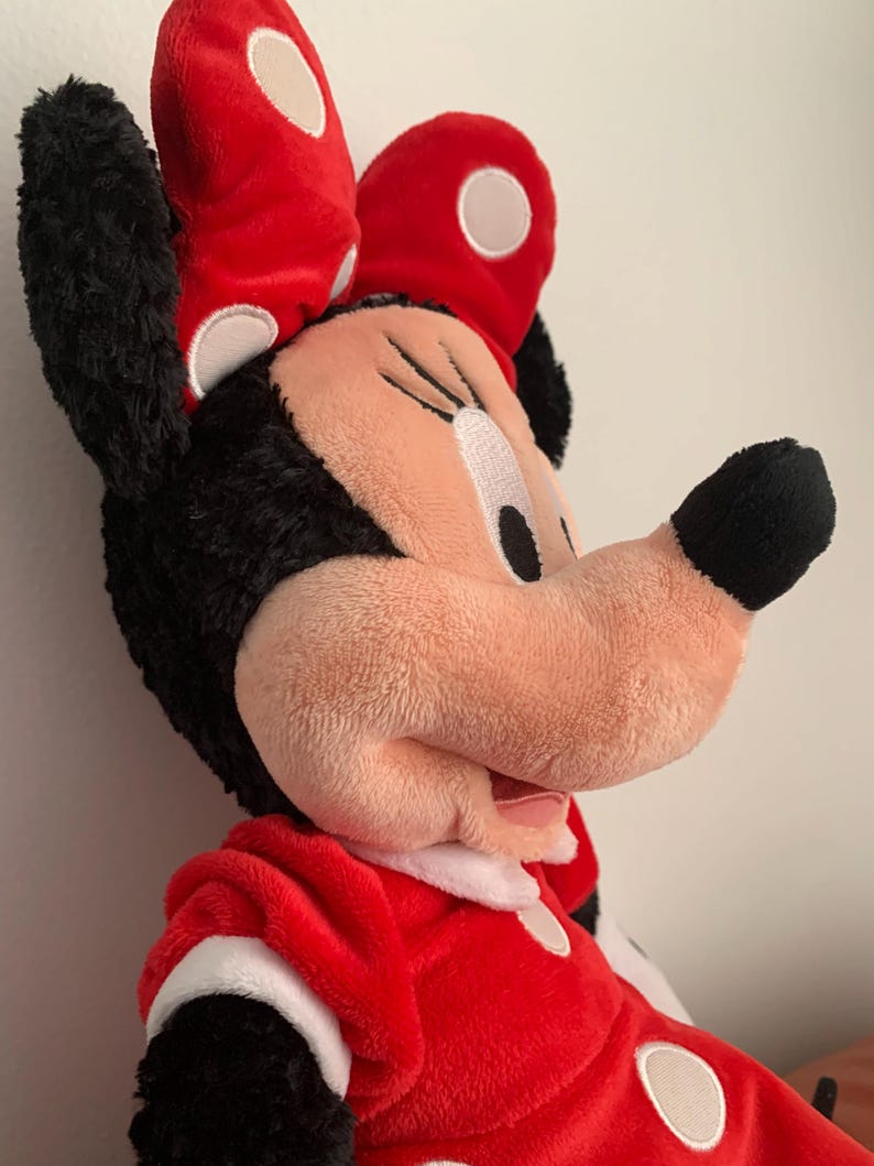 May include: A plush red and black Minnie Mouse toy with white polka dots. The toy is wearing a red bow with white polka dots and a red dress with white polka dots.