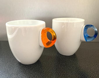 Taza de café Guzzini Art and Café Coffee Feeling, acrílica, con asa naranja y azul, Italia