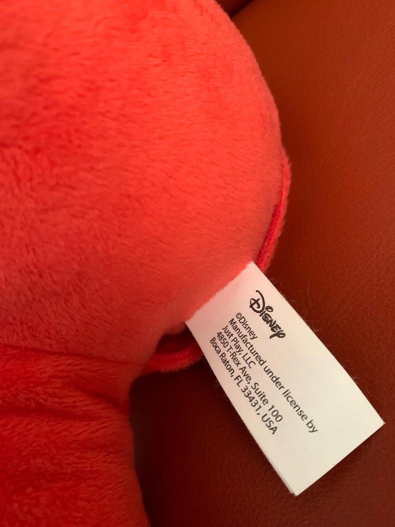 Puede incluir: Una etiqueta blanca con texto negro que dice "&copy;Disney Fabricado bajo licencia de Just Play, LLC 4850 T-Rex Ave, Suite 100 Boca Raton, FL 33431, USA".