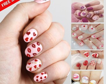 May include: Set of 10 Valentine's Day nail stickers featuring various designs, including hearts, lips, arrows, and glitter. The stickers are shown on a model's nails.